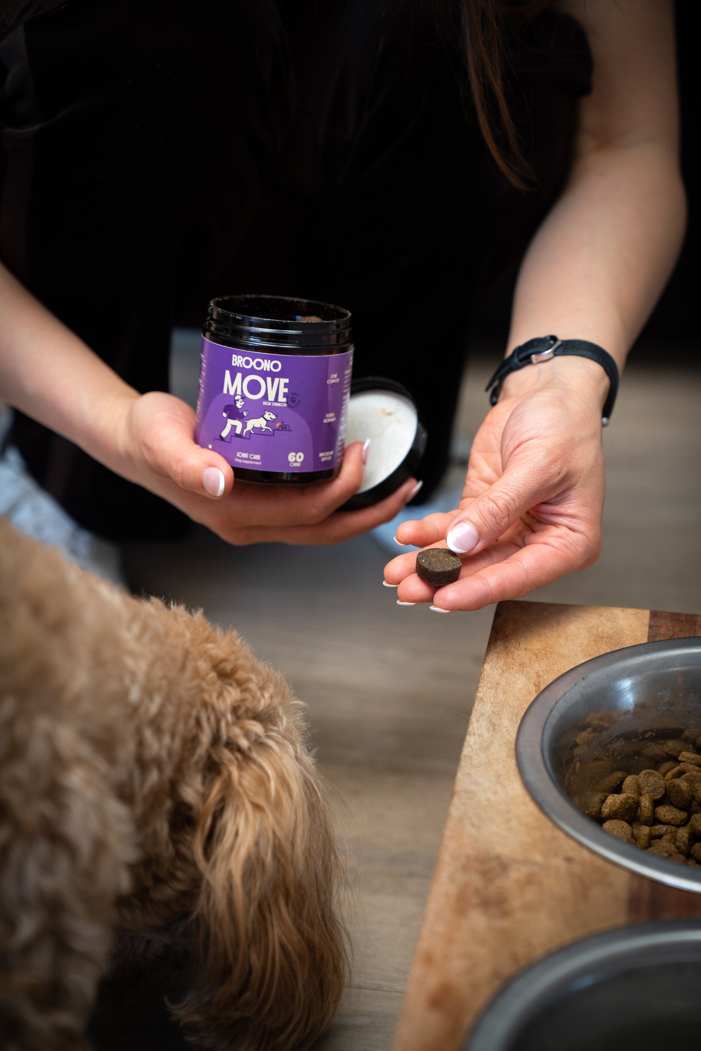 Person holding a Broono Move jar with a dog and food bowl in the background